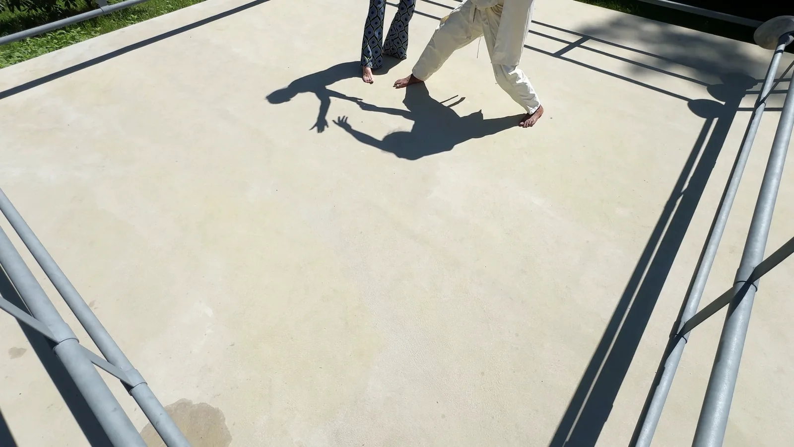 ALOKA · SHADOW — zwei Figuren in Bewegung am oberen Rand, die Schatten greifen ineinander, Standbild