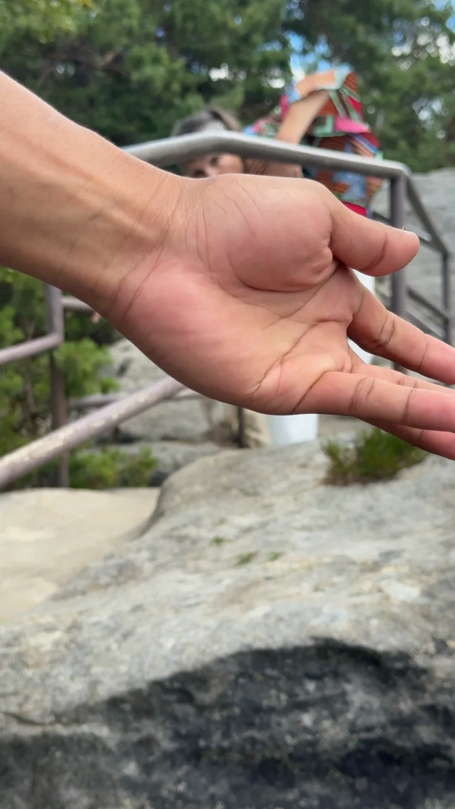 CATCH — eine geöffnete Hand im Vordergrund, dahinter das Geländer, Standbild