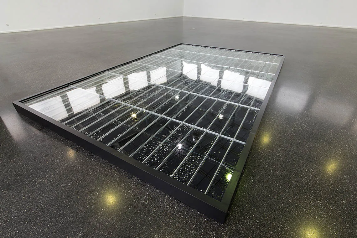 Kondensat III — Bodeninstallation aus Wannen, Glas und kondensiertem Tuschewasser; in der dunklen Fläche spiegeln sich die Fensterraster des Ausstellungsraums, Kunstverein Ludwigshafen 2014