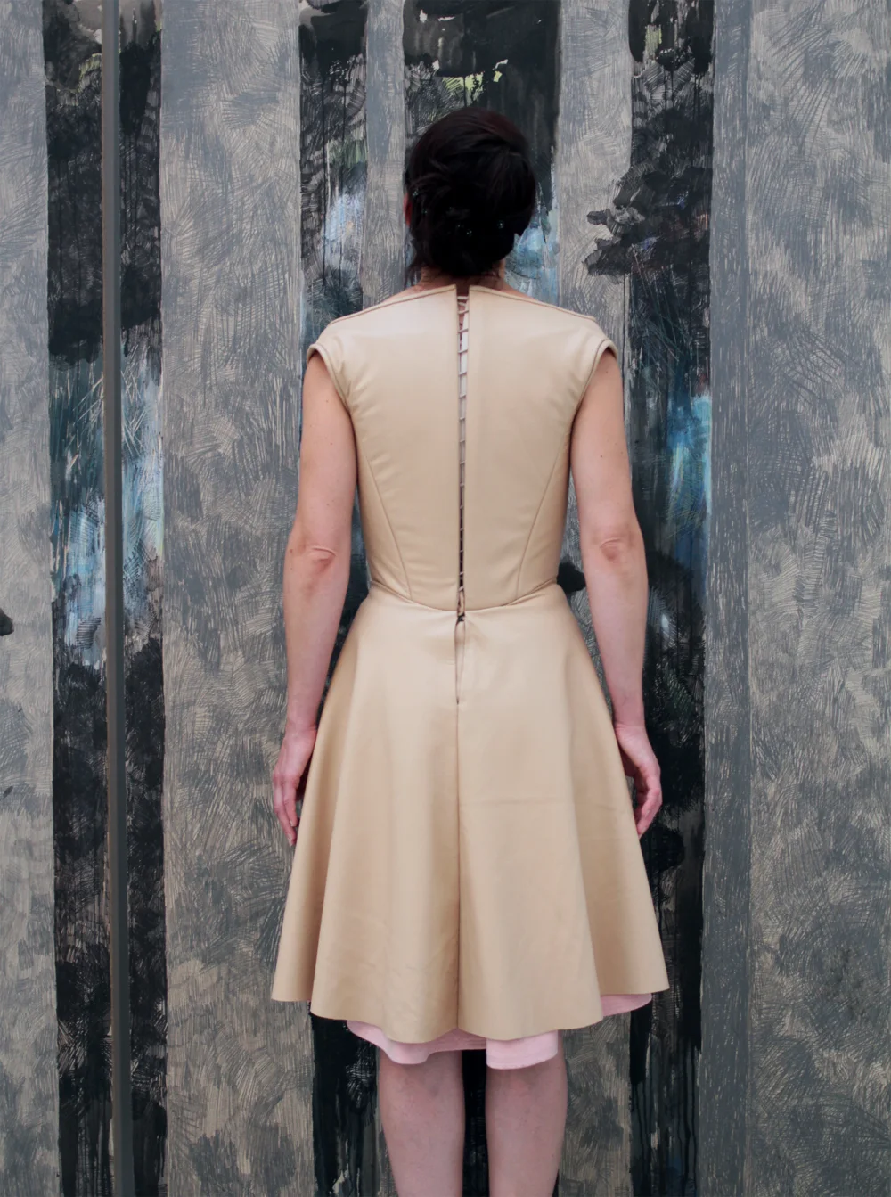 OSCURO — die Künstlerin im hautfarbenen Lederkleid, von hinten, vor der Zeichnung