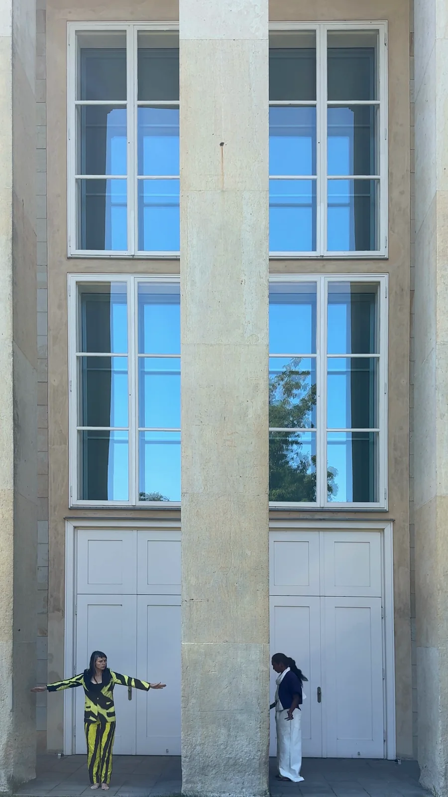 VIYELL — Trema Xtrema und Birgit Schuh stehen links und rechts der Säule vor der hohen Fassade, die Arme ausgebreitet; startet das Video
