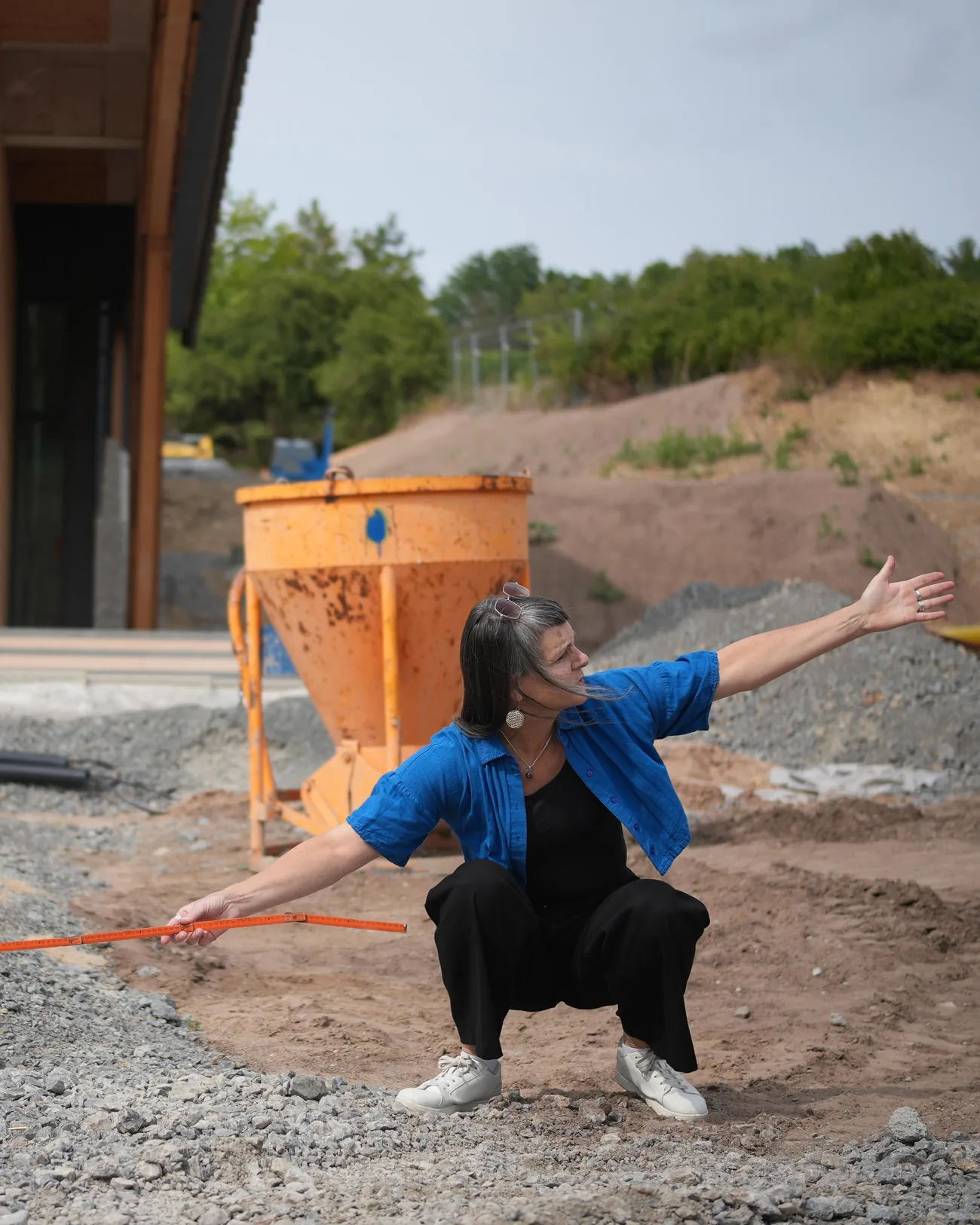 Birgit Schuh misst auf einer Baustelle vor einem Holzbau die Situation aus, Foto: Jonas Schiller